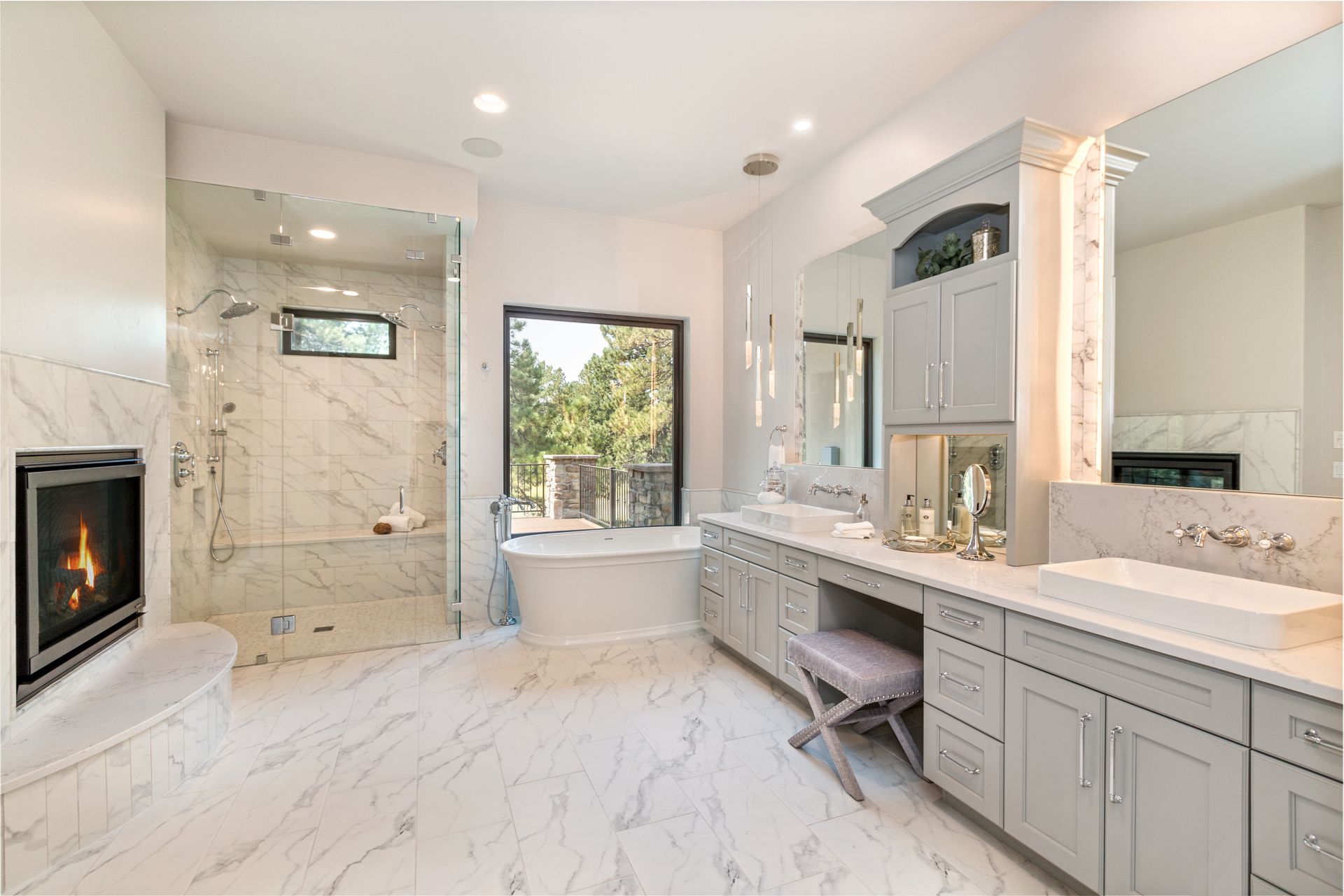 Bright marble bathroom with double vanity, large mirror, fireplace, and walk-in shower.