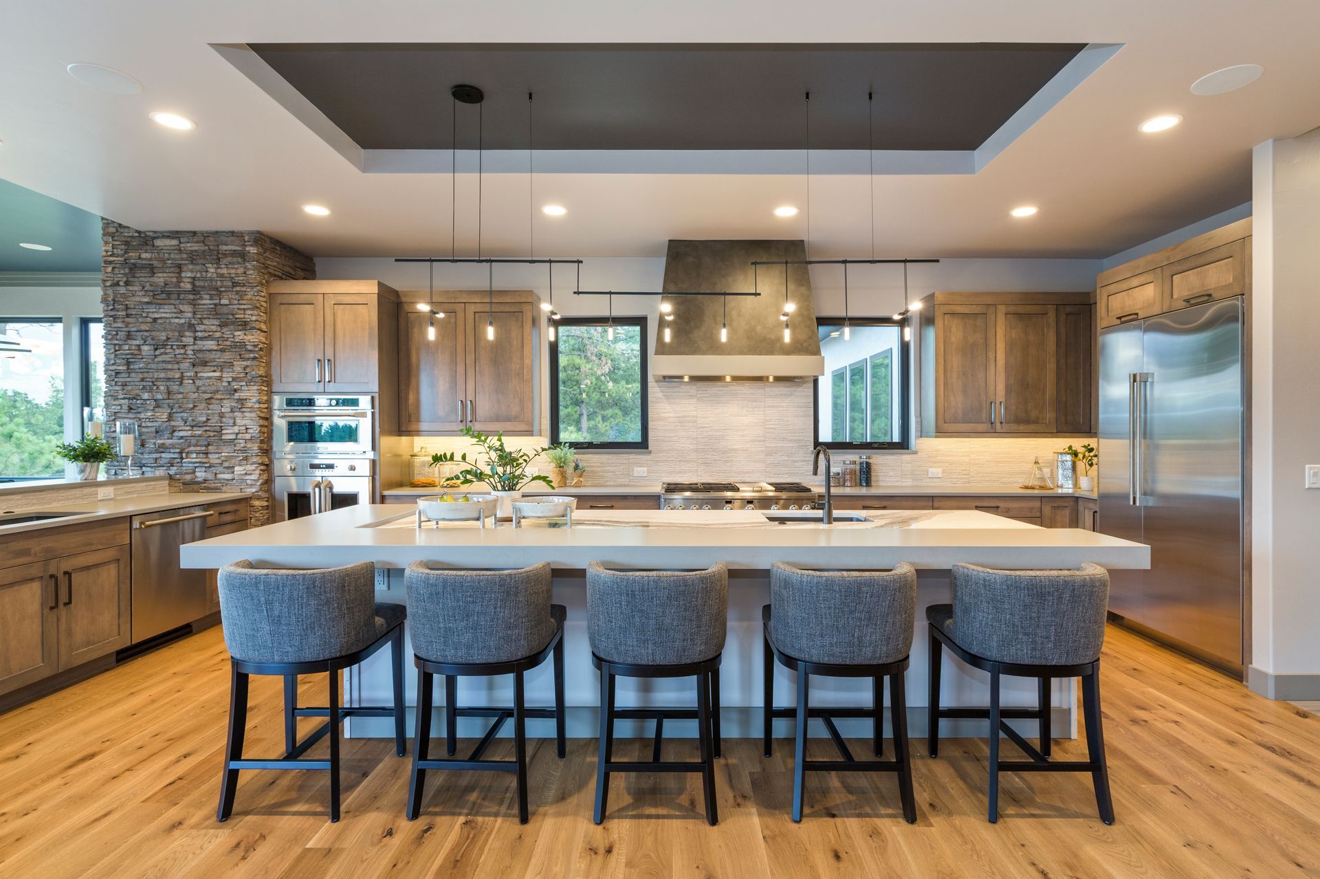 Modern kitchen with large island, five stools, wood cabinets, and stainless steel appliances