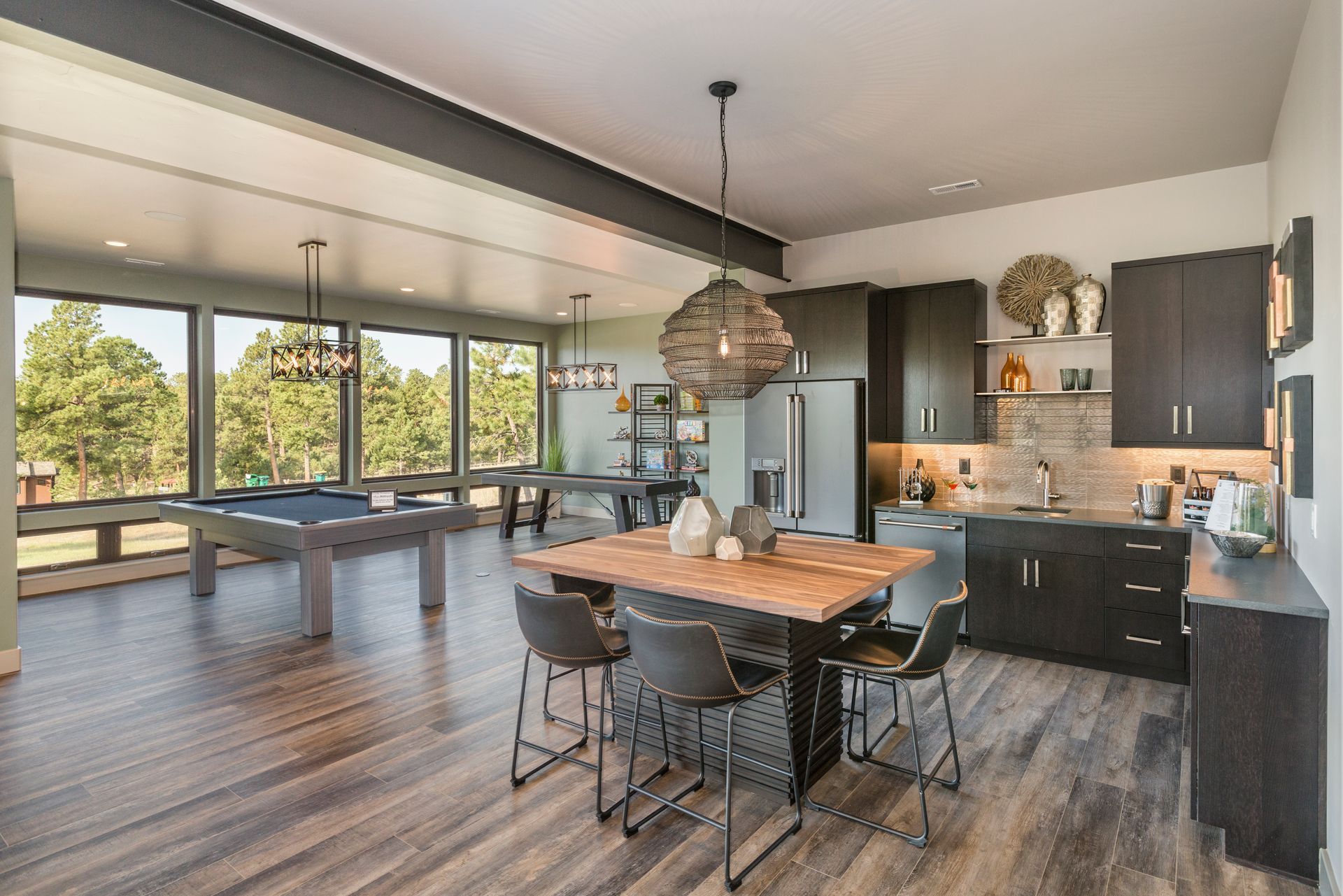 Modern open-plan kitchen and dining area with large windows, dark cabinets, and a wooden table