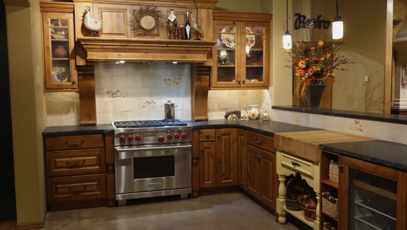 Warm-toned kitchen with wood cabinets, stainless steel stove, and tiled backsplash.