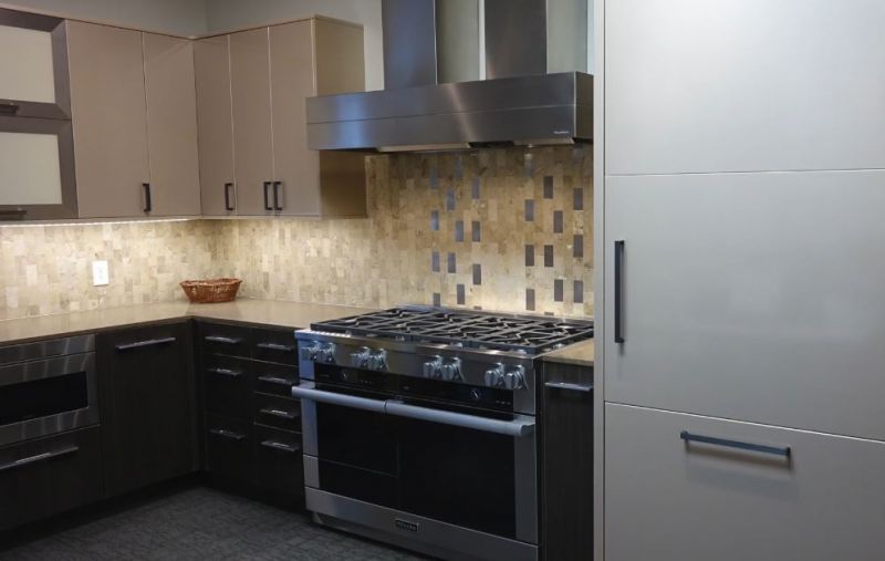 Modern kitchen with black appliances, beige cabinets, mosaic backsplash, and a stainless steel fridge