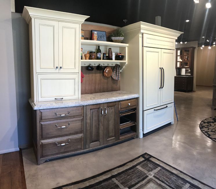 Stylized kitchen cabinet display with cream and wood finishes in a showroom.