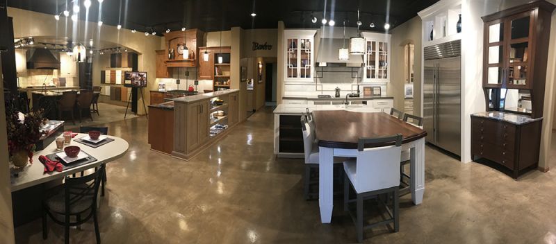 Interior of a furniture showroom with sofas, tables, cabinets, and warm overhead lighting