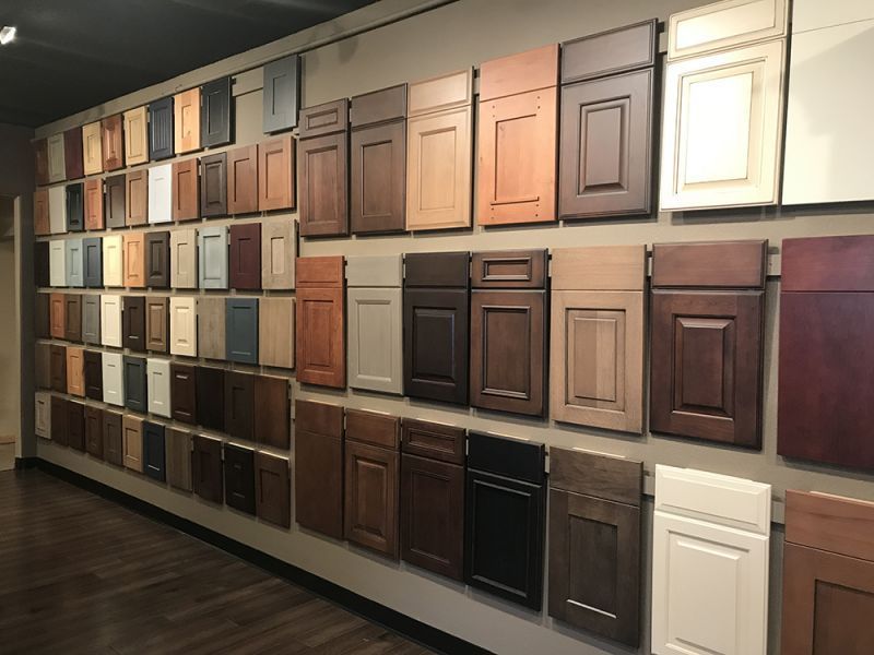 Wall of assorted cabinet door samples in a showroom, arranged in rows with various wood finishes and colors