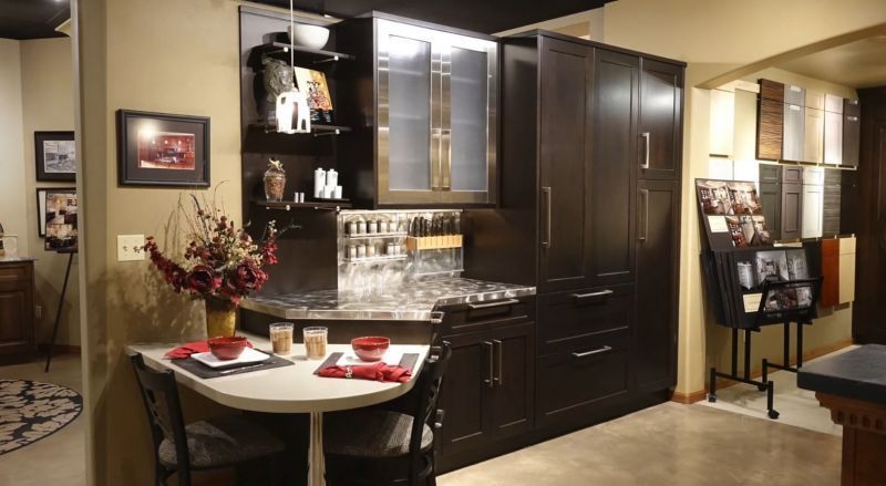 Elegant dining nook with a small round table, red placemats, and dark wood cabinetry in the background
