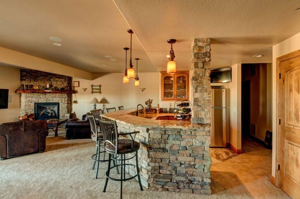 Open-concept kitchen and living room with stone bar, high stools, and fireplace.