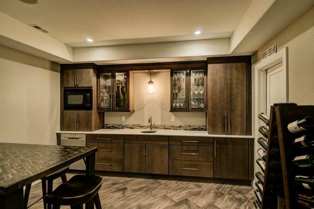 Modern kitchen and bar area with wood cabinets, granite counters, and a tiled floor