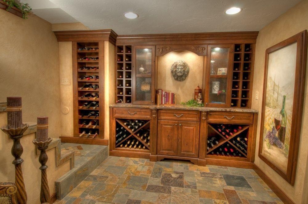 Built-in wine cellar with wooden cabinets, wine racks, and decorative wall art under recessed lighting