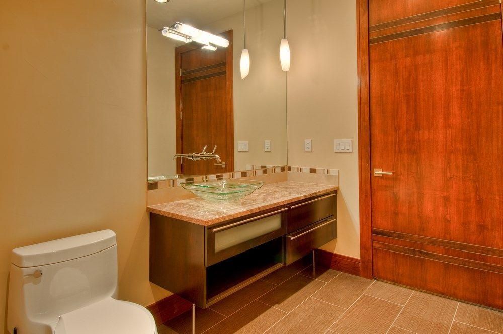 Bathroom with beige walls, marble vanity, mirror, toilet, and large wooden closet door