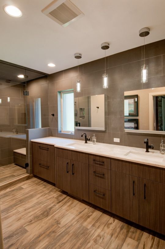 Modern bathroom with double vanity, wood cabinets, large mirrors, and pendant lights