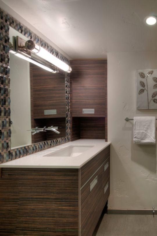Modern bathroom vanity with mirror, wall light, and wood-grain cabinetry