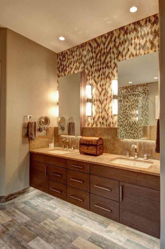 Modern bathroom vanity with double sinks, large mirrors, beige walls, and stone tile flooring.
