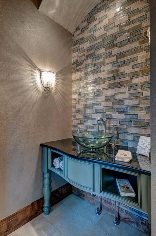 Hallway nook with blue console table, wall sconce, mosaic tile accent wall, and decorative bowl