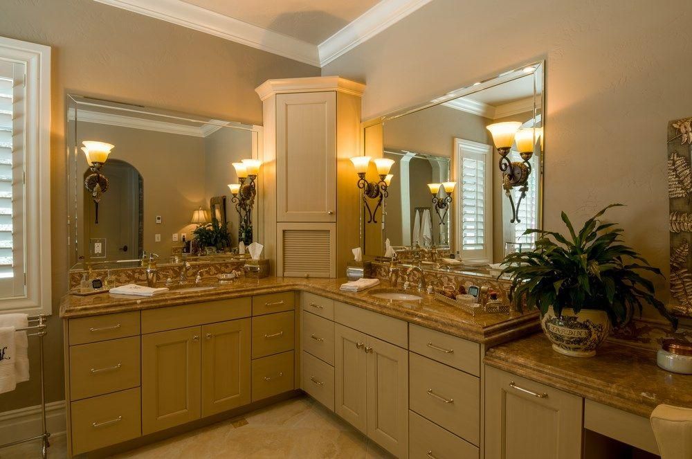 Elegant bathroom vanity with large mirrors, beige cabinets, and warm lighting