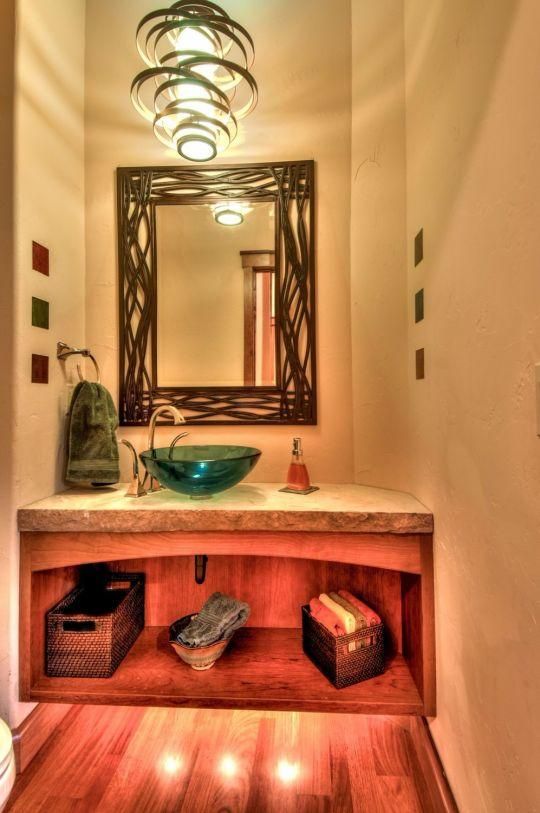 Narrow hallway with a wooden vanity, decorative mirror, glass bowl sink, and warm pendant lights