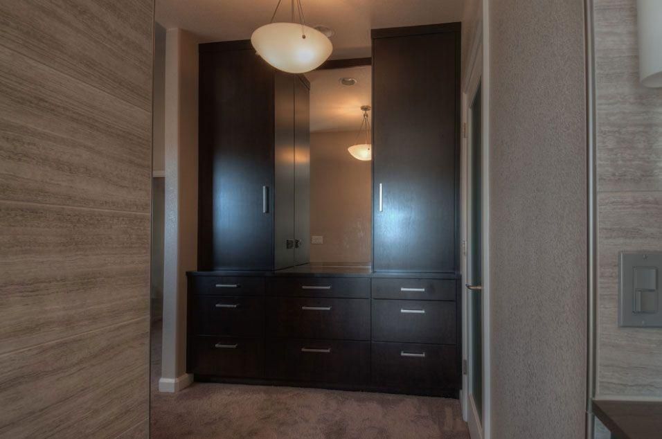 Dark wood built-in wardrobe with mirror and drawers in a carpeted room