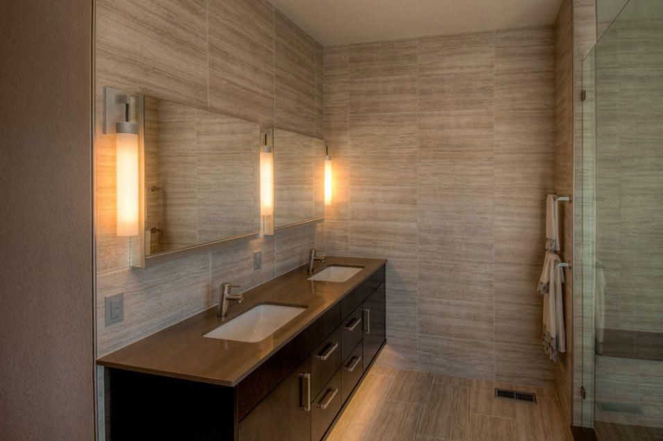 Modern bathroom with double sink vanity, large mirror, and warm wall sconces