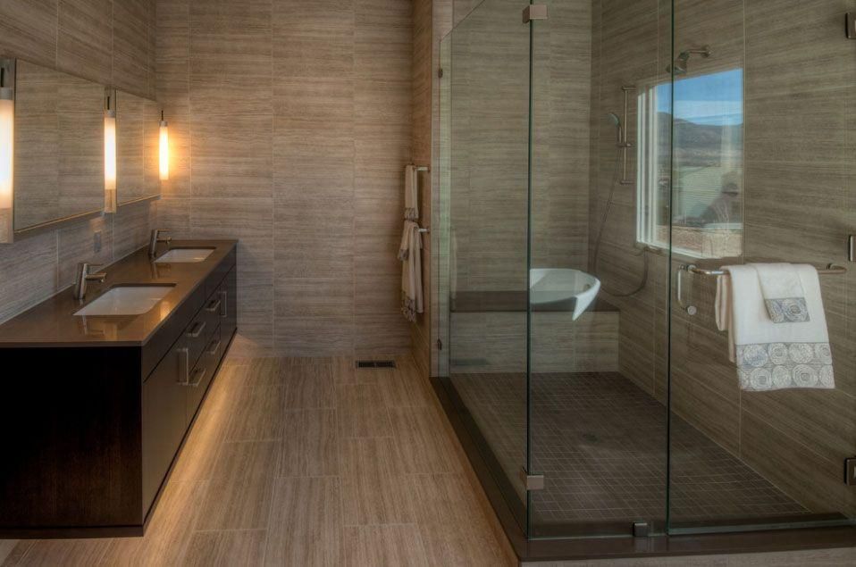 Modern bathroom with wood vanity, glass shower enclosure, and neutral tiled walls