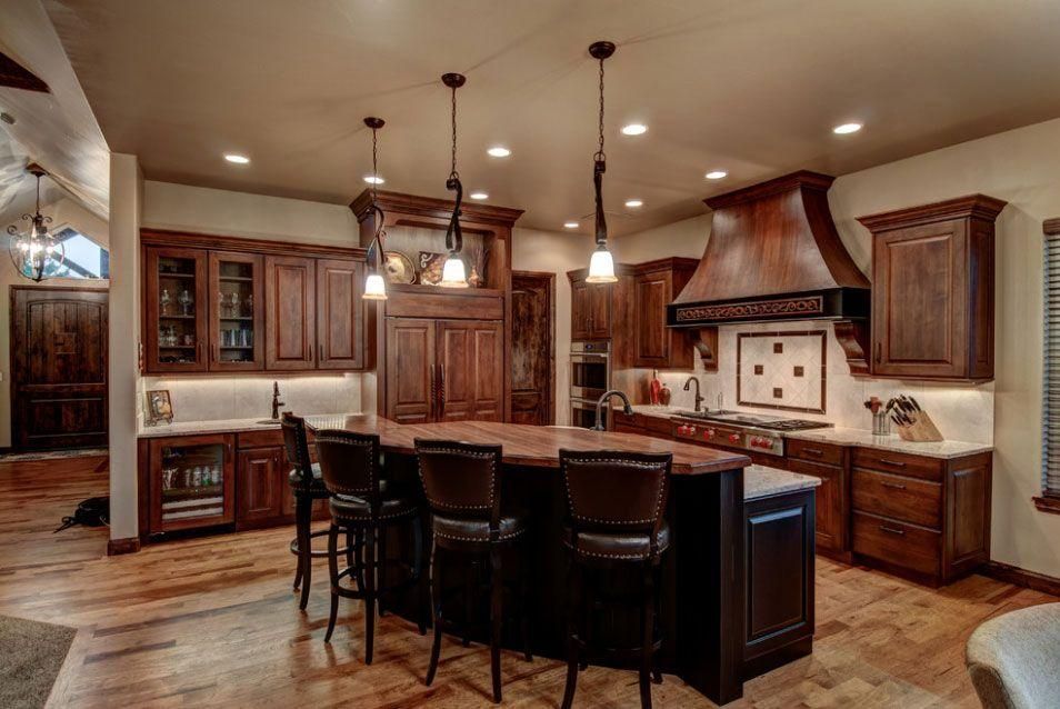 Warm luxury kitchen with dark wood cabinets, island seating, and pendant lights