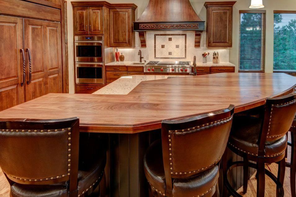 Modern kitchen with large wood island, leather stools, and stainless steel appliances
