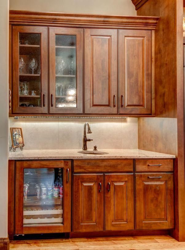 Wooden kitchen cabinets with granite countertop, sink, and glass-front upper cabinet.