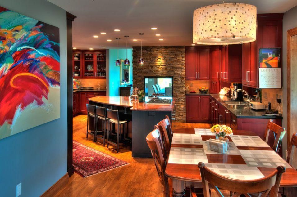 Modern kitchen and dining area with warm wood cabinets, colorful wall art, and a central island