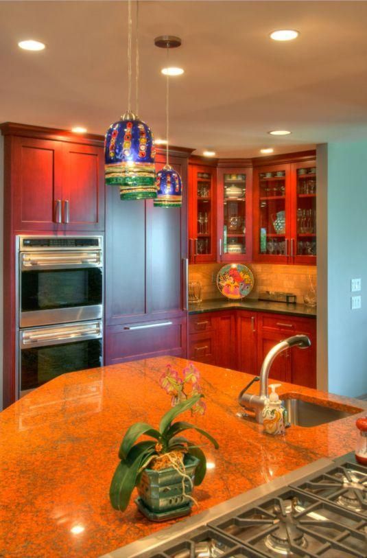 Modern kitchen with orange granite island, stainless appliances, and red wood cabinets