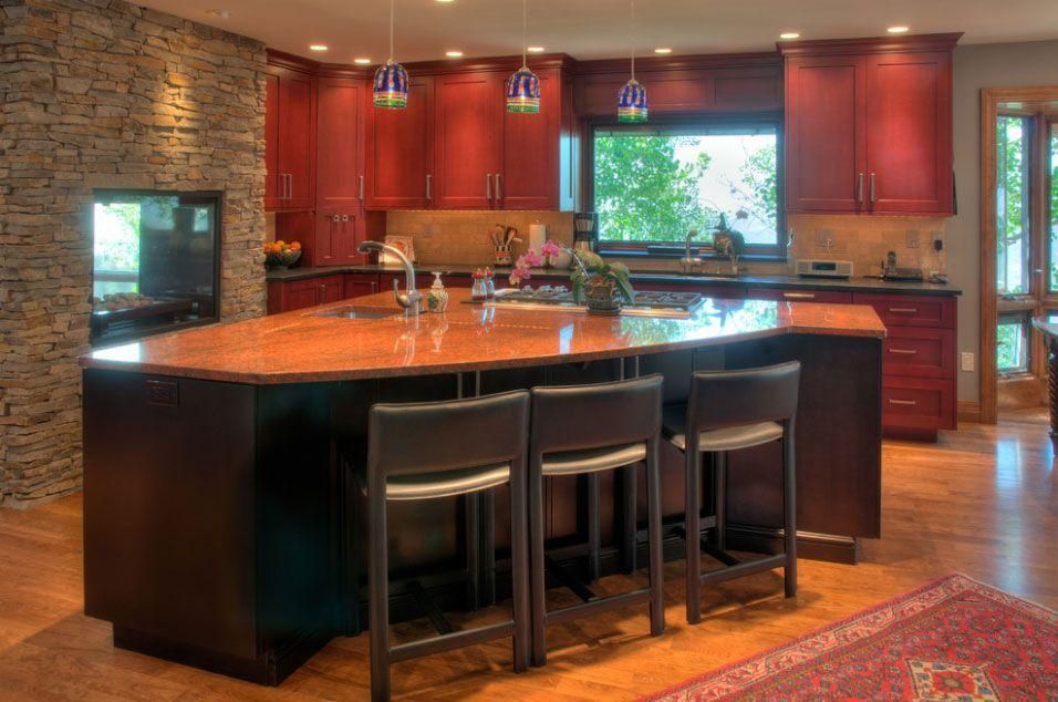 Modern kitchen with a large black island, red cabinets, and a window over the sink