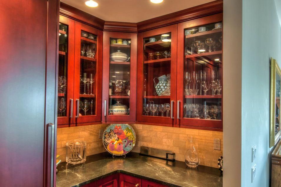 Built-in corner cabinet with glass doors displaying dishes and decor in a warm-lit room