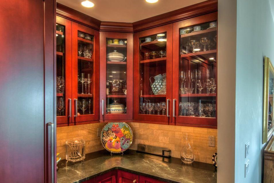 Built-in wooden glass cabinets displaying glassware and decor in a corner bar nook