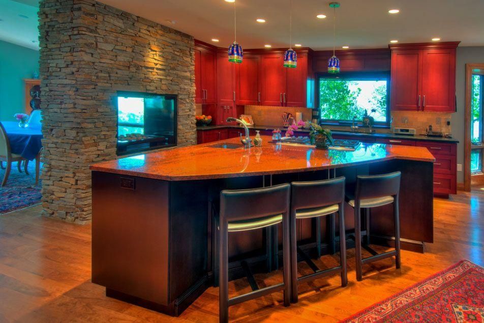 Modern kitchen with a large island, dark wood cabinets, stone accents, and warm lighting