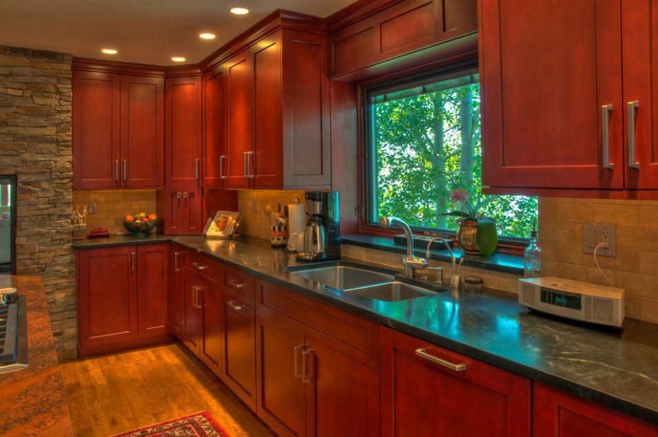 Warm-toned kitchen with cherry cabinets, granite counters, and a large window over the sink.