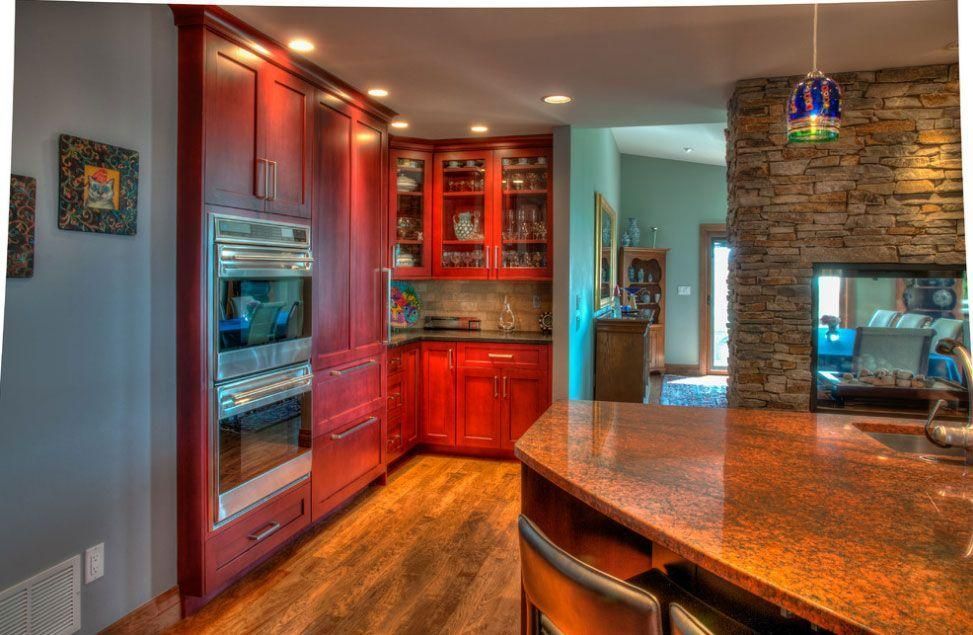 Modern kitchen with red cabinets, stainless steel appliances, and stone island countertop