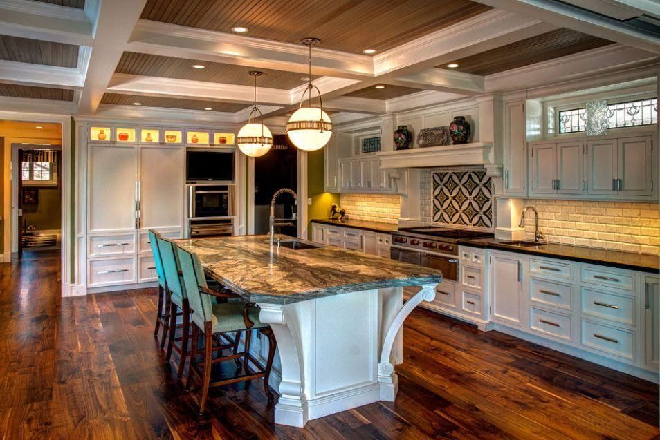 Bright gourmet kitchen with granite island, white cabinets, and dark wood floors