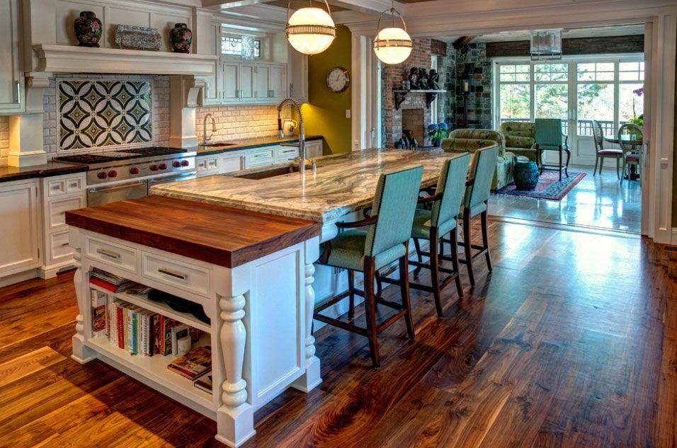 Bright kitchen with a large island, bar stools, and hardwood floors, opening to a sunlit dining area