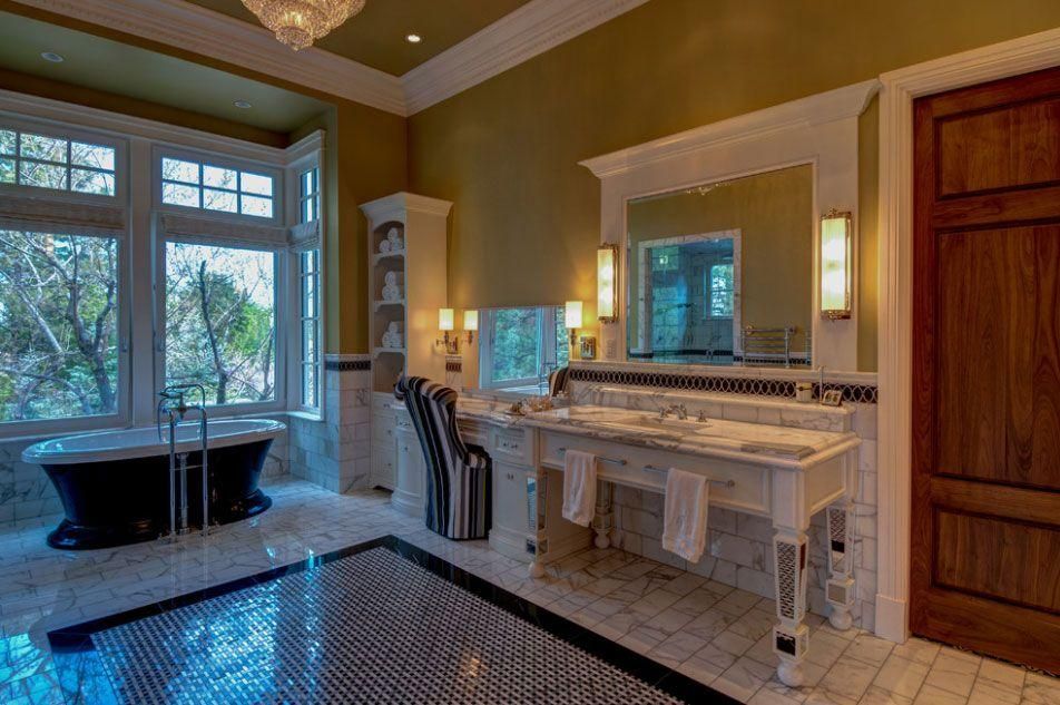 Elegant bathroom with marble vanity, large tub, and bay window with trees outside