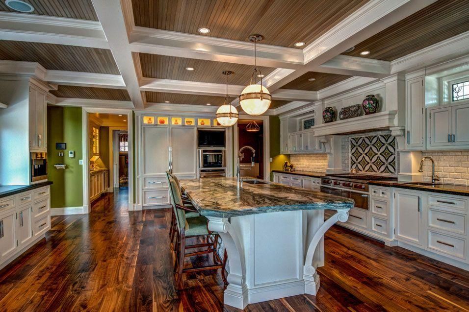 Bright modern kitchen with white cabinets, wood floors, a large island, and pendant lights