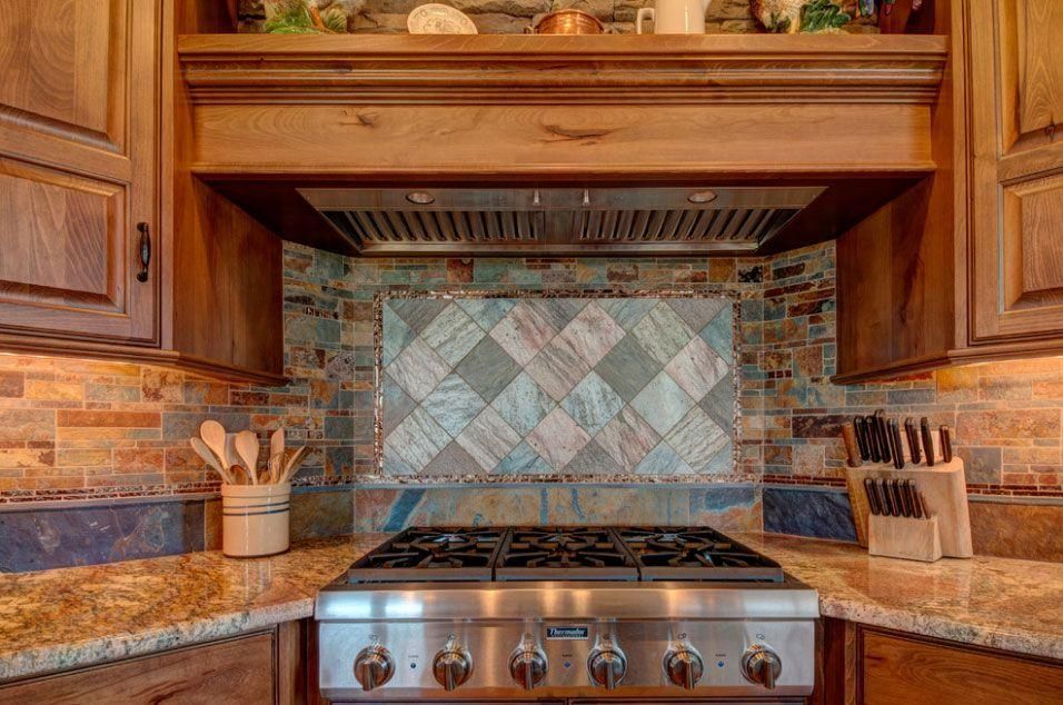 Kitchen stovetop with stainless range, stone backsplash, wood cabinets, and granite countertop