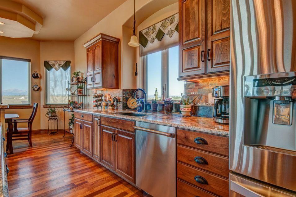 Modern kitchen with wooden cabinets, stainless steel appliances, and a large window with a scenic view
