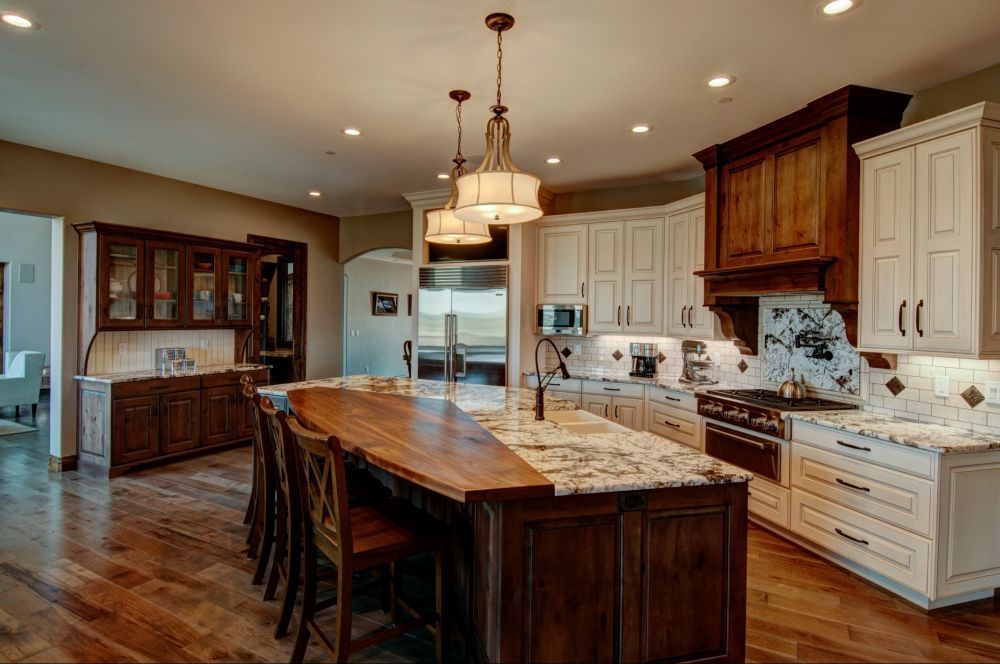 Spacious kitchen with a large wooden island, white cabinets, and warm pendant lighting.
