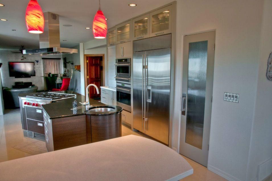 Modern kitchen with stainless steel appliances, island, and red pendant lights