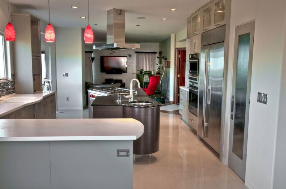Modern kitchen with stainless steel appliances, pendant lights, and a living area in the background