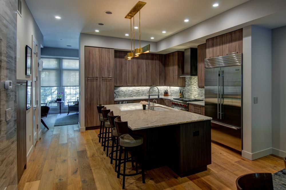 Modern kitchen with wood cabinets, marble island, bar stools, and stainless steel appliances