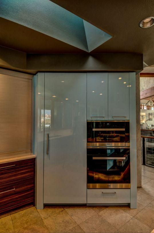 Modern kitchen with a gray built-in refrigerator and oven under blue accent lighting