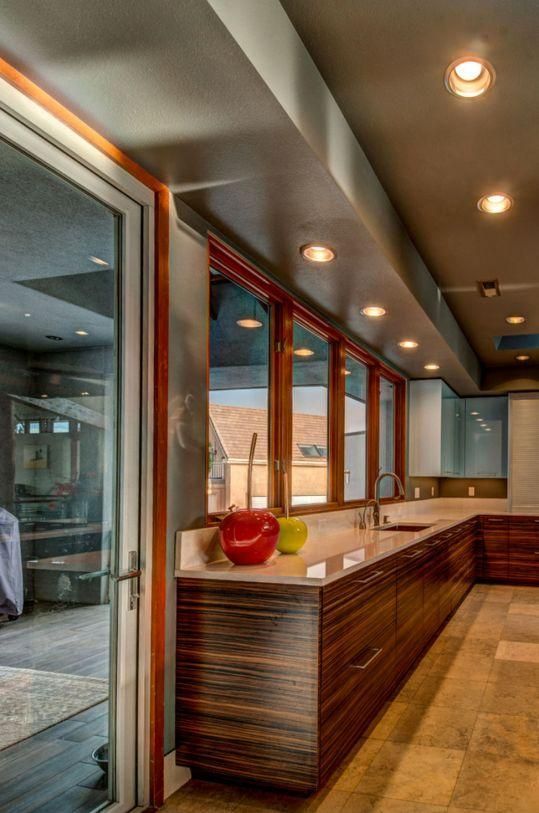 Modern indoor/outdoor bar with wood counter, recessed lights, and red glass decor by large windows