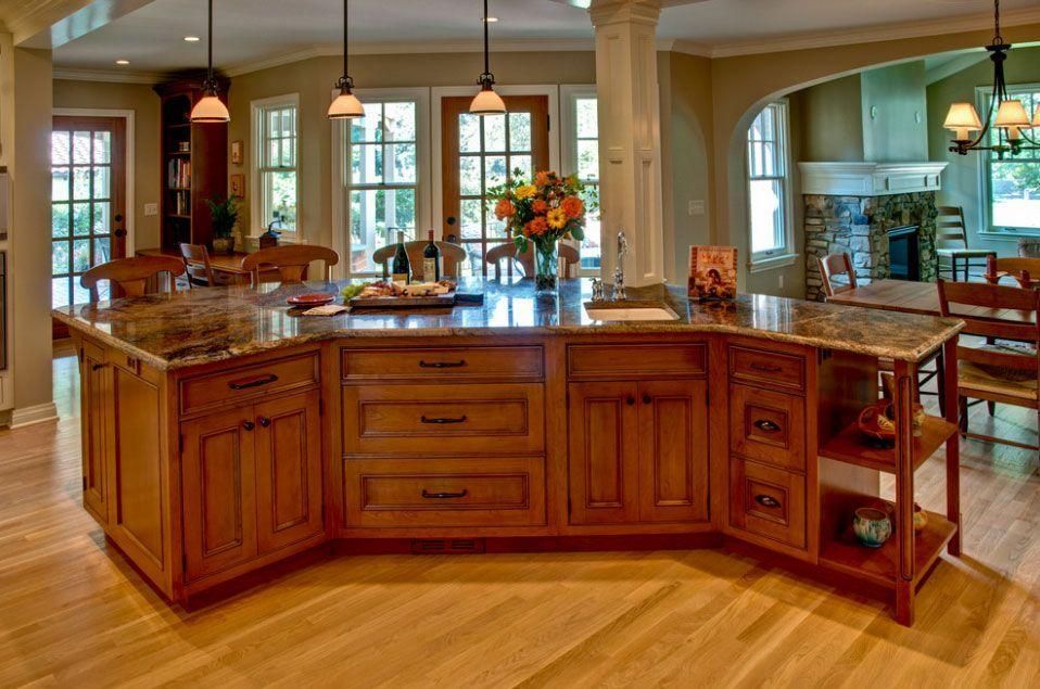 Spacious kitchen with a large wooden island, pendant lights, and a vase of flowers in the center.