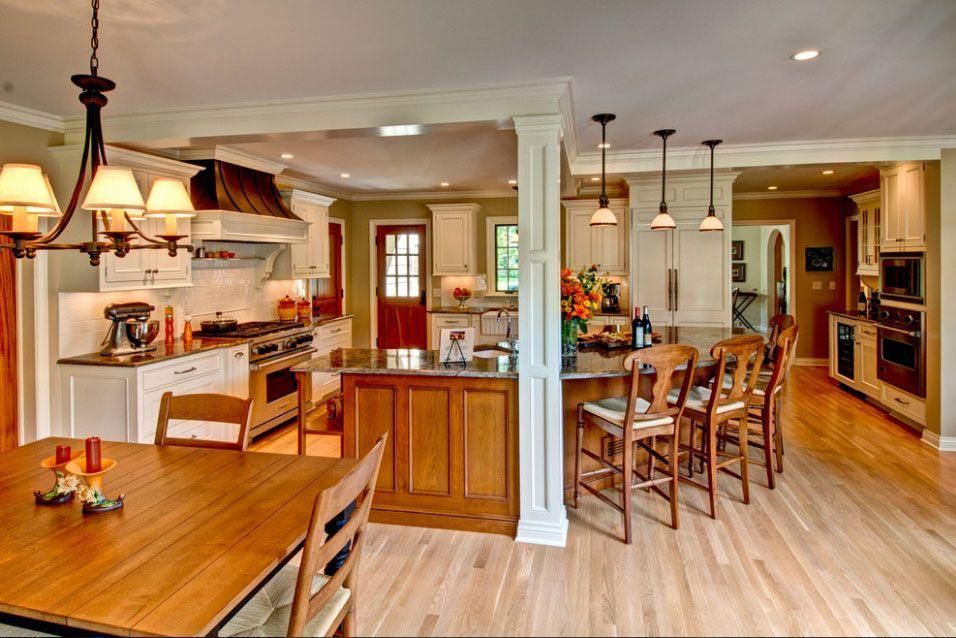 Bright open-plan kitchen and dining room with wood floors, island, and hanging lights