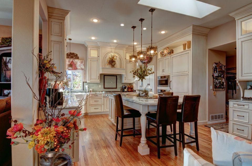 Bright kitchen with island seating, white cabinets, hardwood floors, and skylight-lit dining area