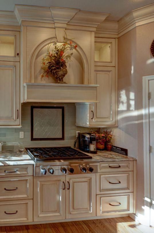 Elegant cream-colored kitchen with stovetop, custom cabinets, and decorative wreath above the range hood
