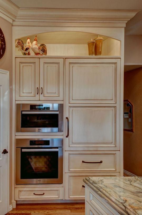 Built-in kitchen cabinetry with stainless oven and microwave, cream-colored panels, and marble countertop.